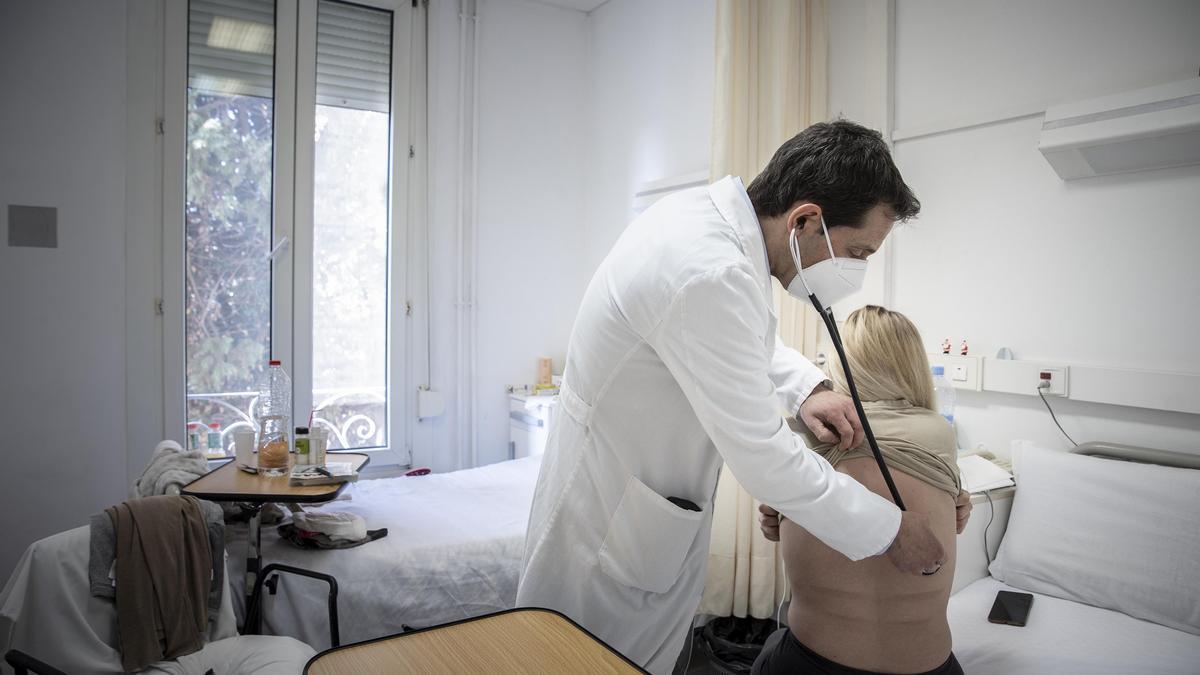 Un doctor de la clínica de Barcelona ausculta a una paciente.