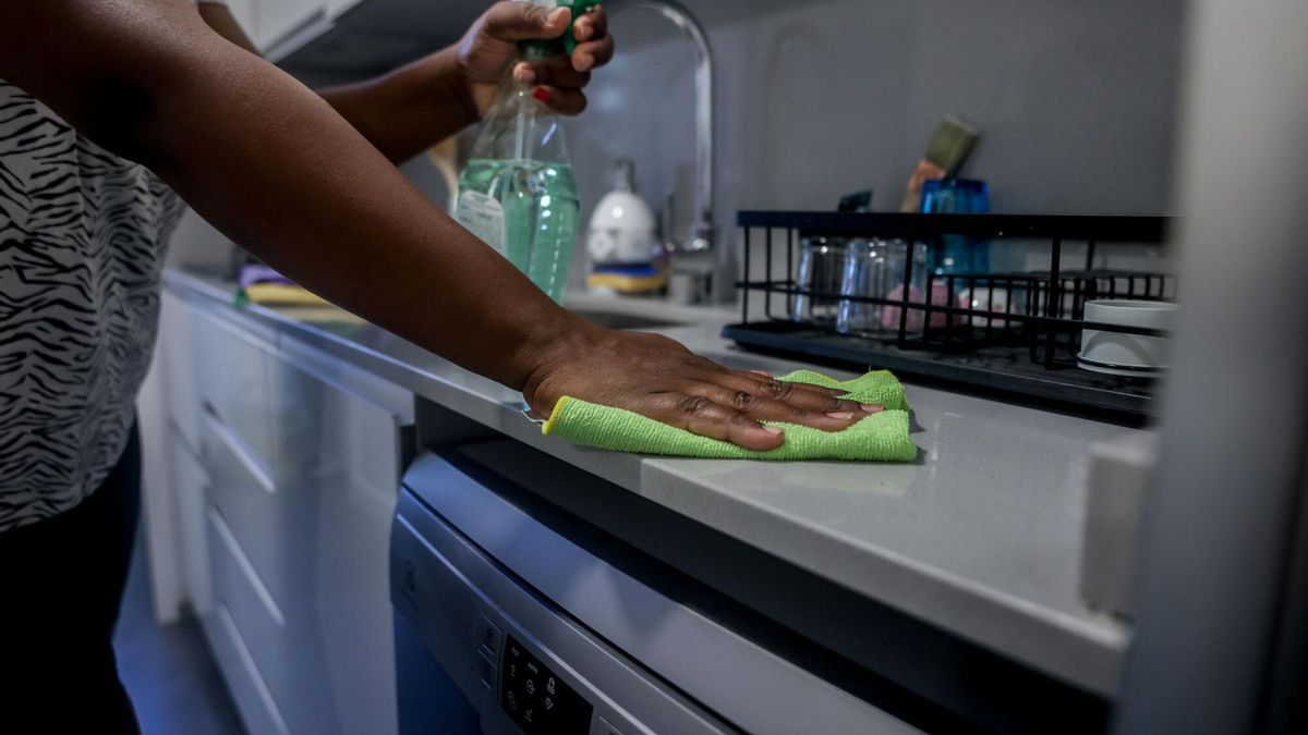 Una empleada de hogar limpia la encimera de la cocina.