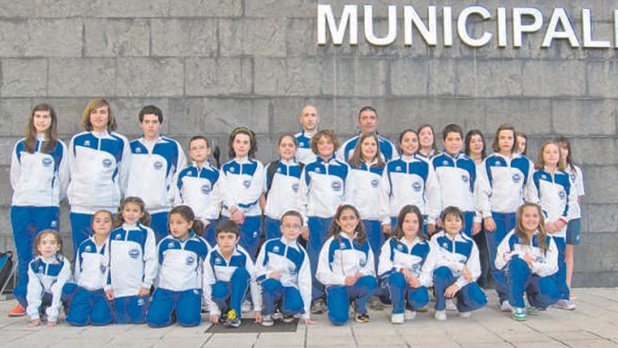 Algunos de los nadadores de la escuela posan ante la fachada de la piscina corverana.