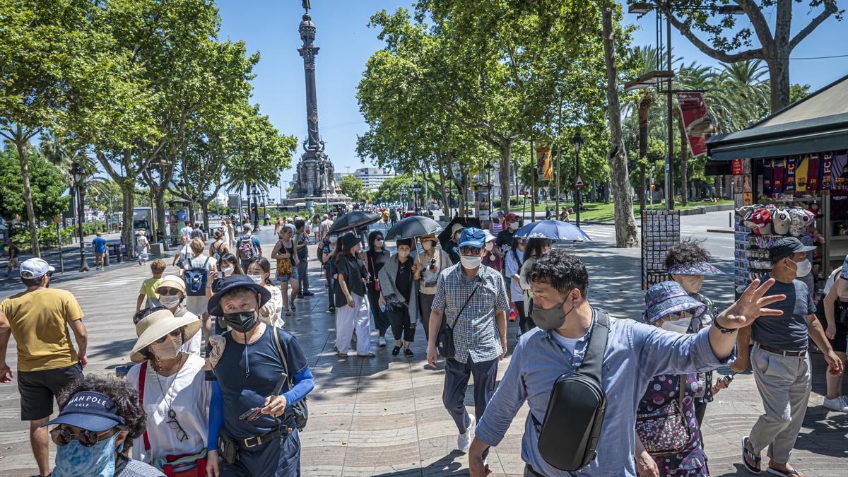 Un grupo de turistas japoneses se pasean por las Ramblas ataviados de paraguas para hacer frente al sol, el pasado día 12.