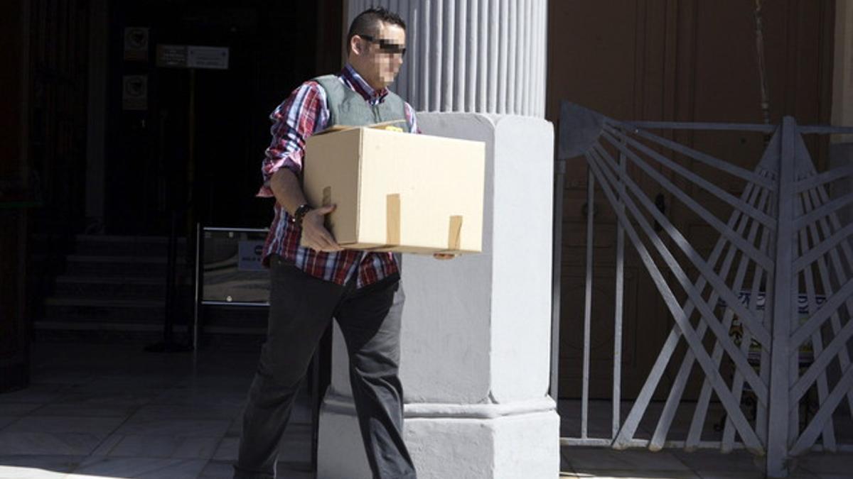 Un agente sale de dependencias municipales con una caja con documentos.