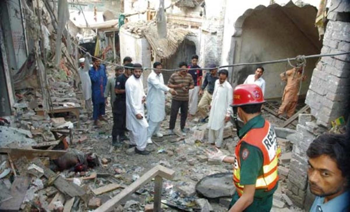 Transeünts observen la destrucció provocada per una bomba a Pak Pattan, al Panjab pakistanès. La bomba estava col·locada en una motocicleta, que va explosionar al seu pas per un lloc sant sufí.