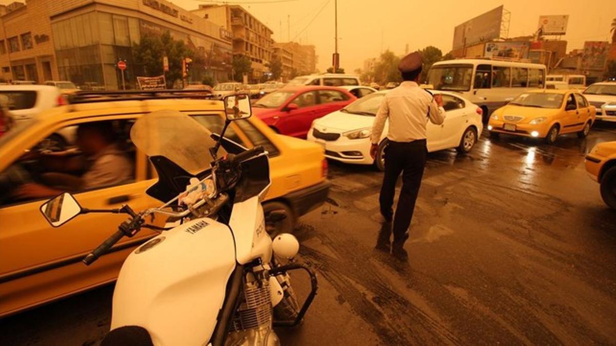 Un policía iraquí organiza el tráfico en Bagdad en medio de una tormenta de arena.