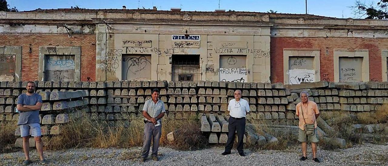 La directiva de la Asociación de Amigos del Chicharra, ante la que fue estación principal de la línea de Villena a Alcoy y Yecla y que se encuentra abandonada.