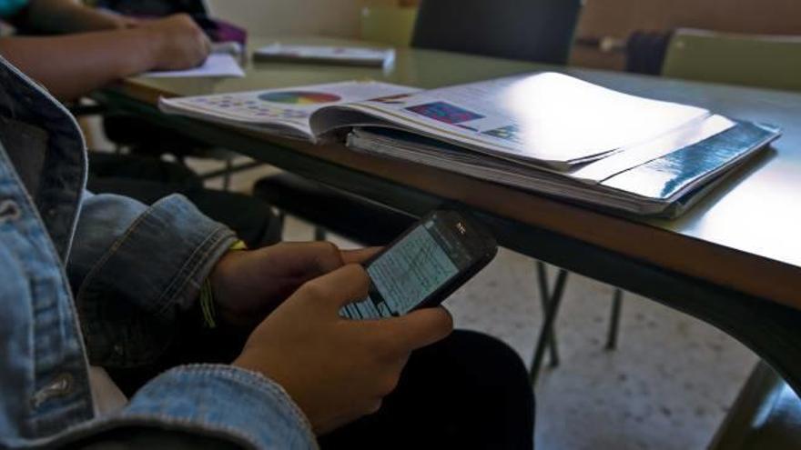 Un adolescente wasapea con su móvil durante una clase.