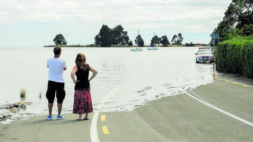 Una parella observa una carretera inundada  a Nord-amèrica.  | SHUTTERSTOCK