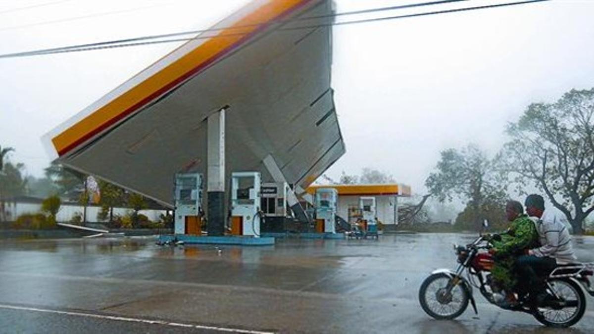 Un motorista pasa por delante del tejado de una gasolinera tumbado por el tifón 'Megi', en Cauayán, en la provincia filipina de Isabela, ayer.