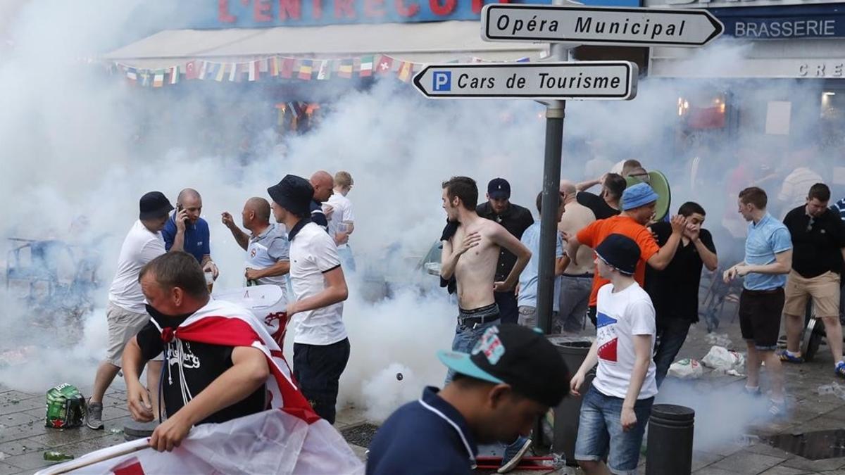 Aficionados ingleses corren tras el lanzamiento de gases lacrimógenos por la policía en Marsella.