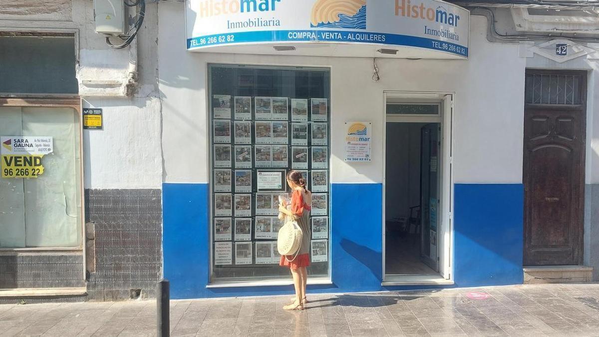 Una joven observa los anuncios de una inmobiliaria de Sagunt.