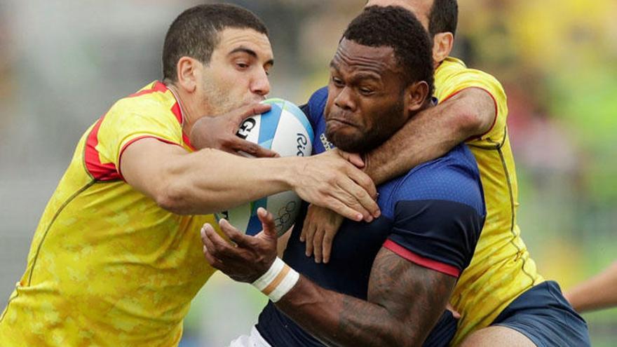 Dos jugadores de la selección española tratan de frenar a un francés.