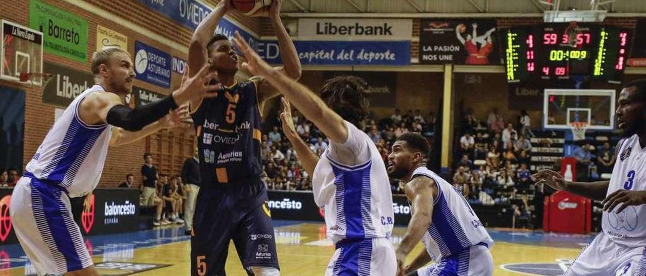 Tre&#039; Coggins, rodeado de jugadores del Almansa, se dispone a tirar a canasta el sábado en el polideportivo de Pumarín.