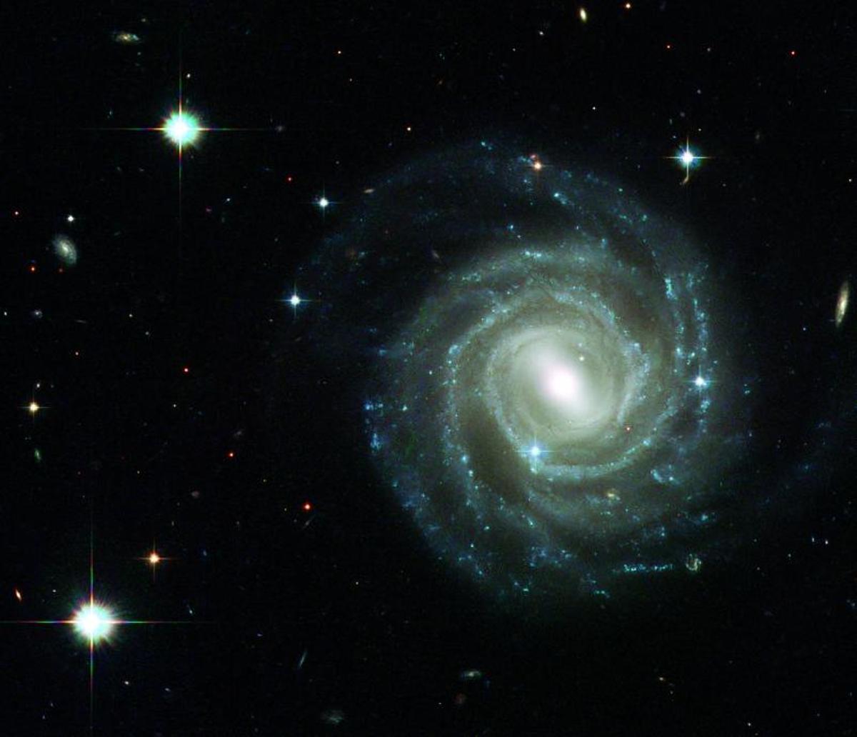 UGC12158 es una galaxia tipo disco con brazos espirales y una barra de estrellas, como nuestra Vía Láctea. Pero ¿qué ocurre en su centro? ¿Cómo ha sido su vida hasta ahora? ¿Se parece realmente a nuestra Galaxia? | | ESA - HUBBLE