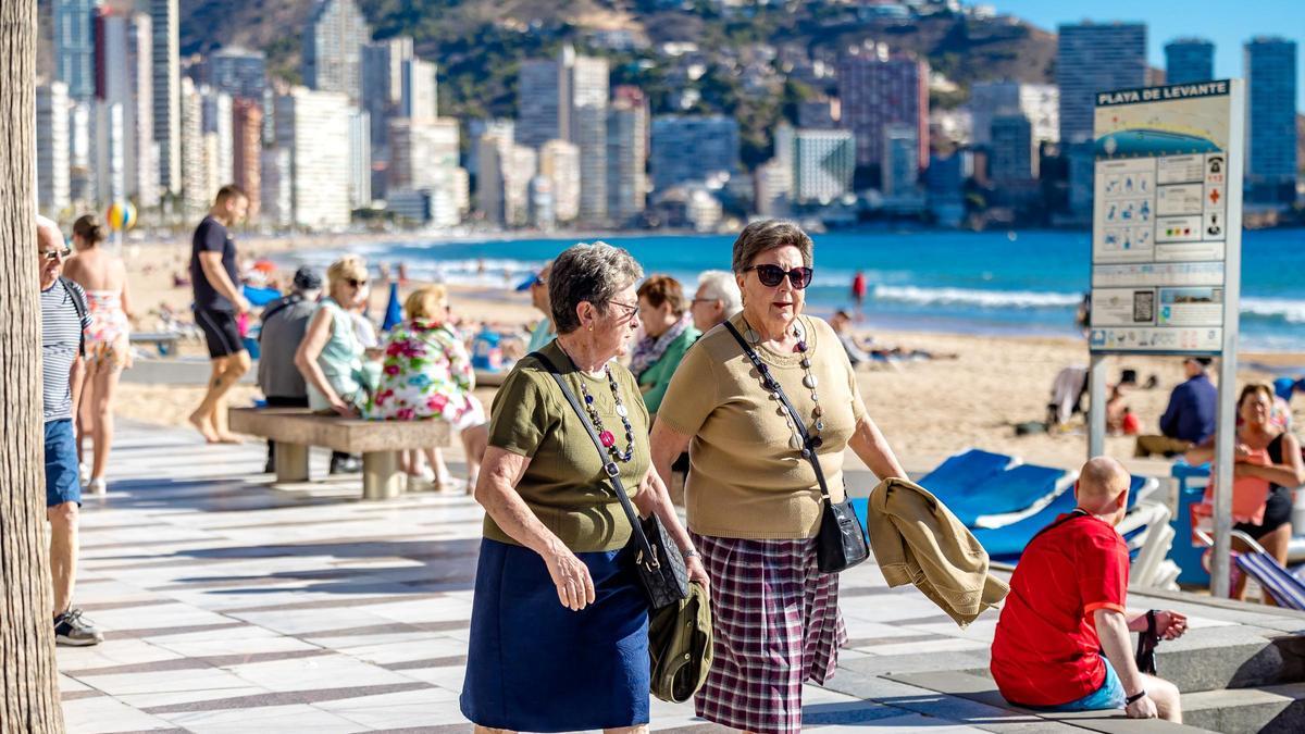 Dos personas mayores paseando por la playa de Benidorm.
