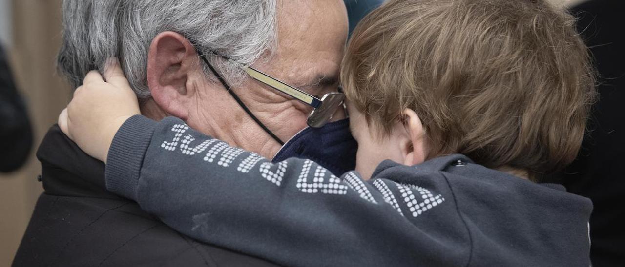 Un nieto sonríe con su nieto en brazos.