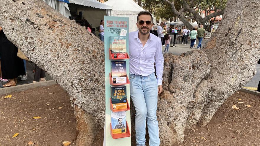 El periodista y coach Curro Cañete, ayer, en la Feria del Libro de Las Palmas, junto a un stand con sus últimas cuatro obras.  | | LP/DLP