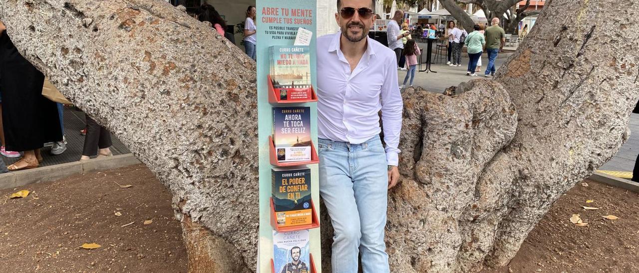 El periodista y coach Curro Cañete, ayer, en la Feria del Libro de Las Palmas, junto a un stand con sus últimas cuatro obras.  | | LP/DLP