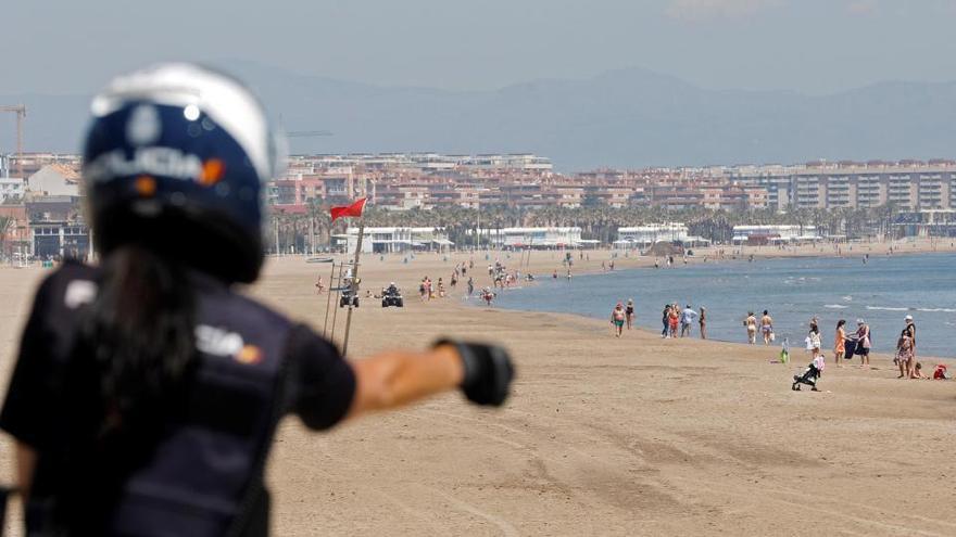 Una agente de la Policía Nacional realiza labores de control en la playa de la Malvarrosa.