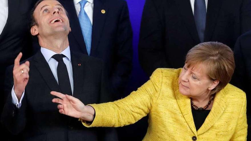 Macron y Merkel reaccionan al sobrevuelo de un dron filmador durante la foto de familia. // Reuters