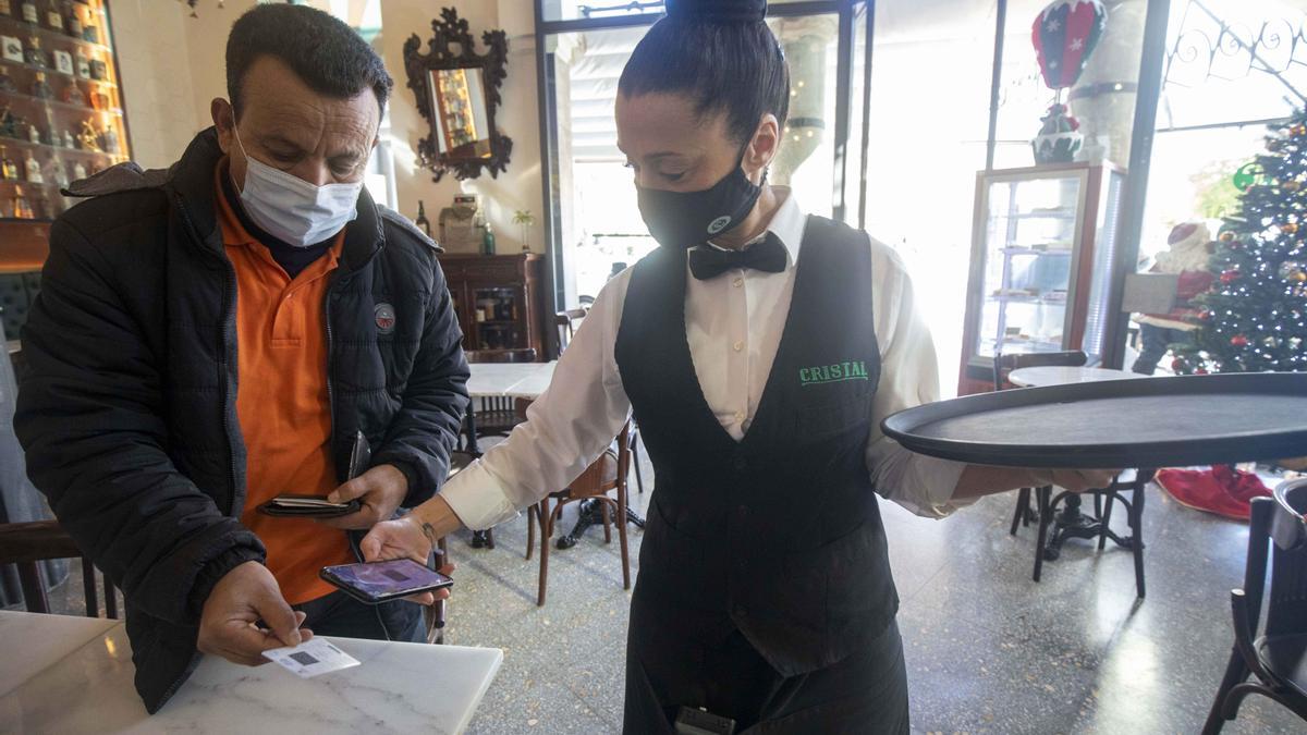 Una camarera del Bar Cristal escanea el certificado covid de un cliente en el interior del popular local palmesano