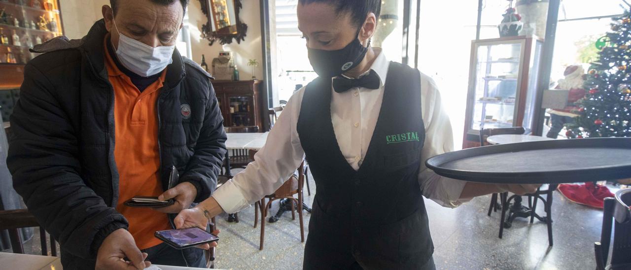 Una camarera del Bar Cristal escanea el certificado covid de un cliente en el interior del popular local palmesano