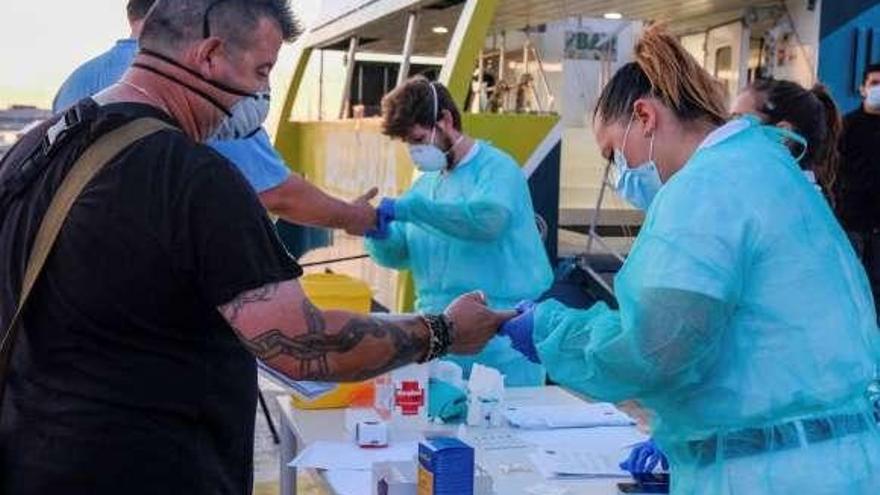 Dos hombres, ayer, en una terraza en La Gomera. A la derecha, controles de temperatura y test rápido de coronavirus en Ibiza para viajar en ferri a Formentera.