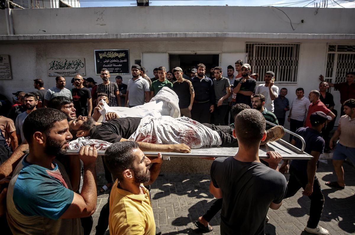 Ciudadanos palestinos portan el cuerpo de un combatiente muerto durante el asalto a los asentamientos israelíes, en el hospital Al-Shifa en la ciudad de Gaza, este sábado.