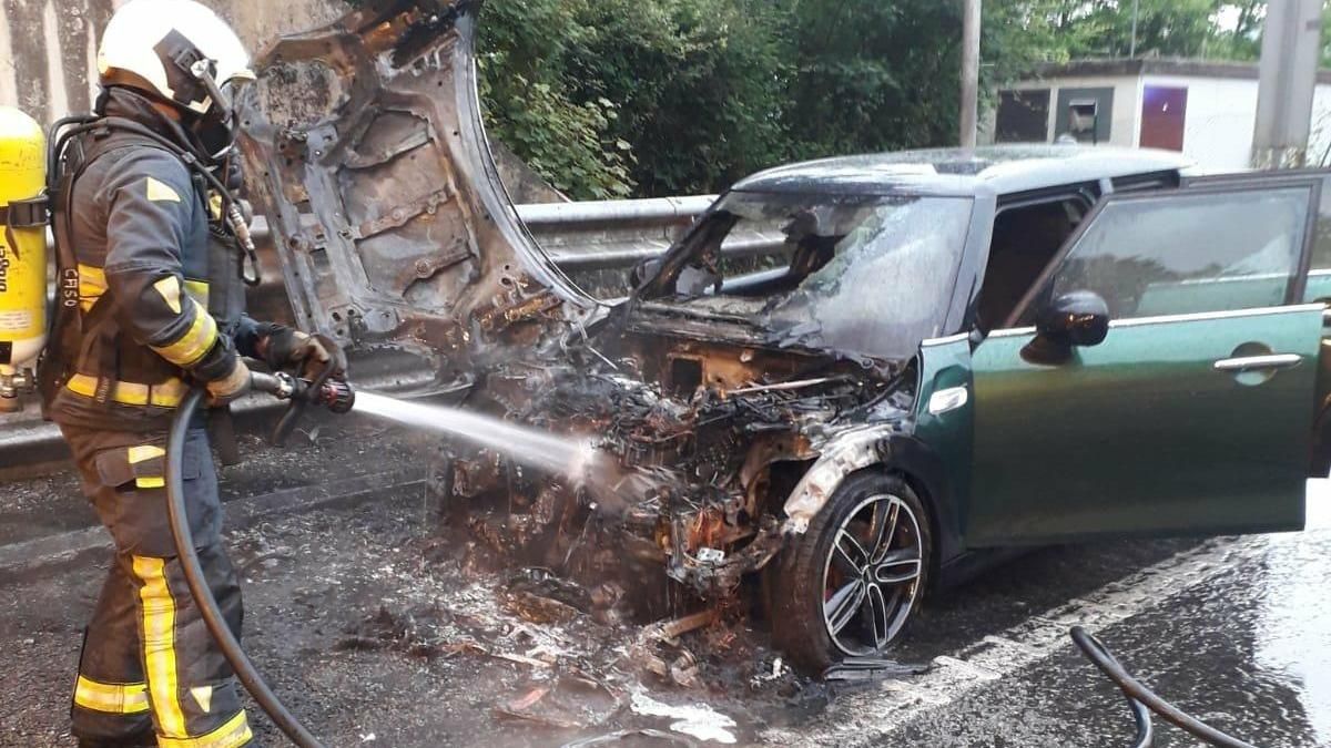Los bomberos junto al coche incendiado