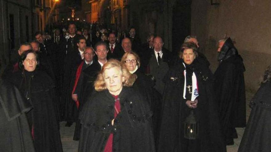 Hermanos y hermanas de la cofradía procesionan por la calle de San Antón y al fondo el Cristo del Amparo. Foto