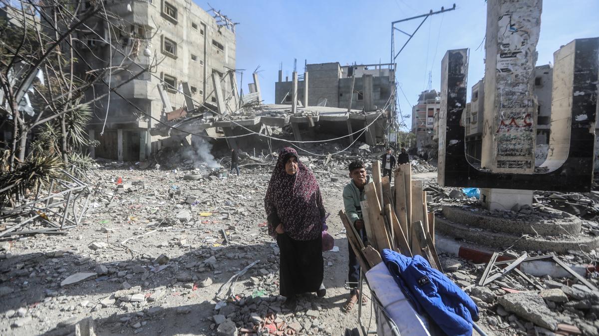 Palestins al costat d'edificis destruïts pels bombardejos a la Franja de Gaza