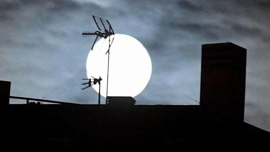 Vista de la luna sobre un tejado de A Coruña, ayer, al anochecer.