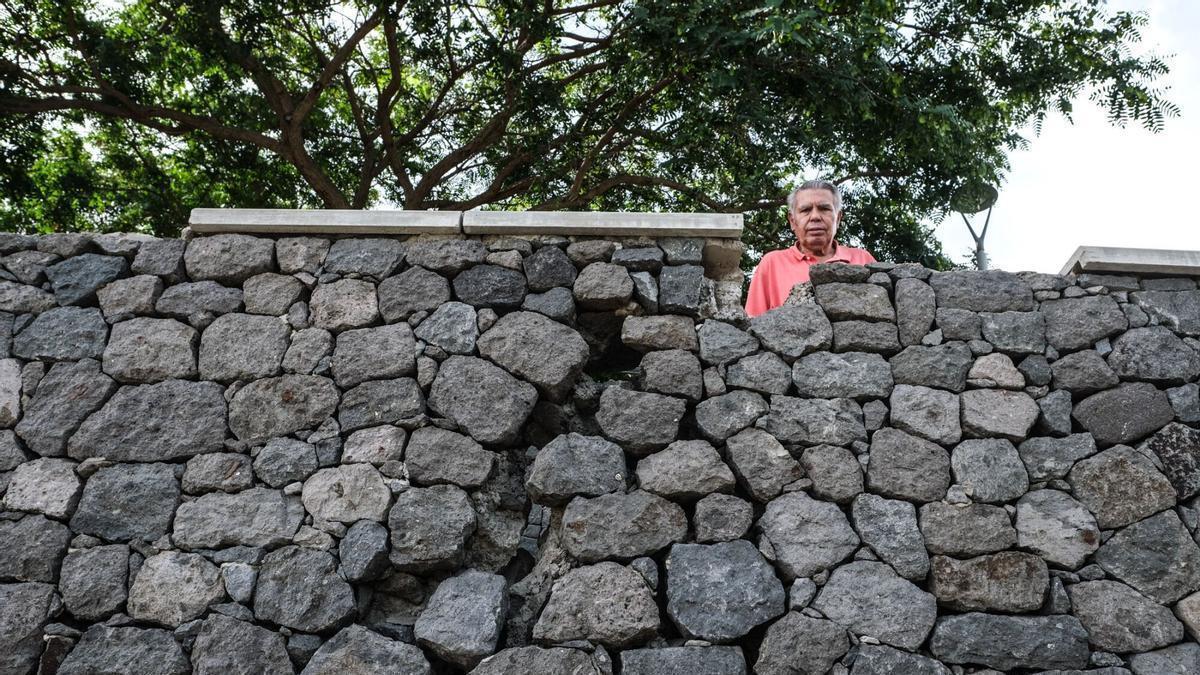 Un vecino se asoma al muro deteriorado de la plaza Isla Perdida.