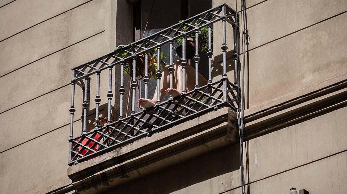 Una mujer disfruta del sol desde su balcón, en un edificio de Barcelona, el 12 de mayo.