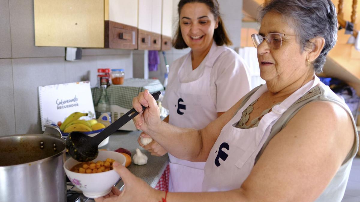 Reyes Ojeda, usuaria del Servicio de Ayuda a Domicilio,  y María del Mar Quevedo, auxiliar de Clece, preparan una de las recetas incluidas en el libro ‘Saboreando Recuerdos’.