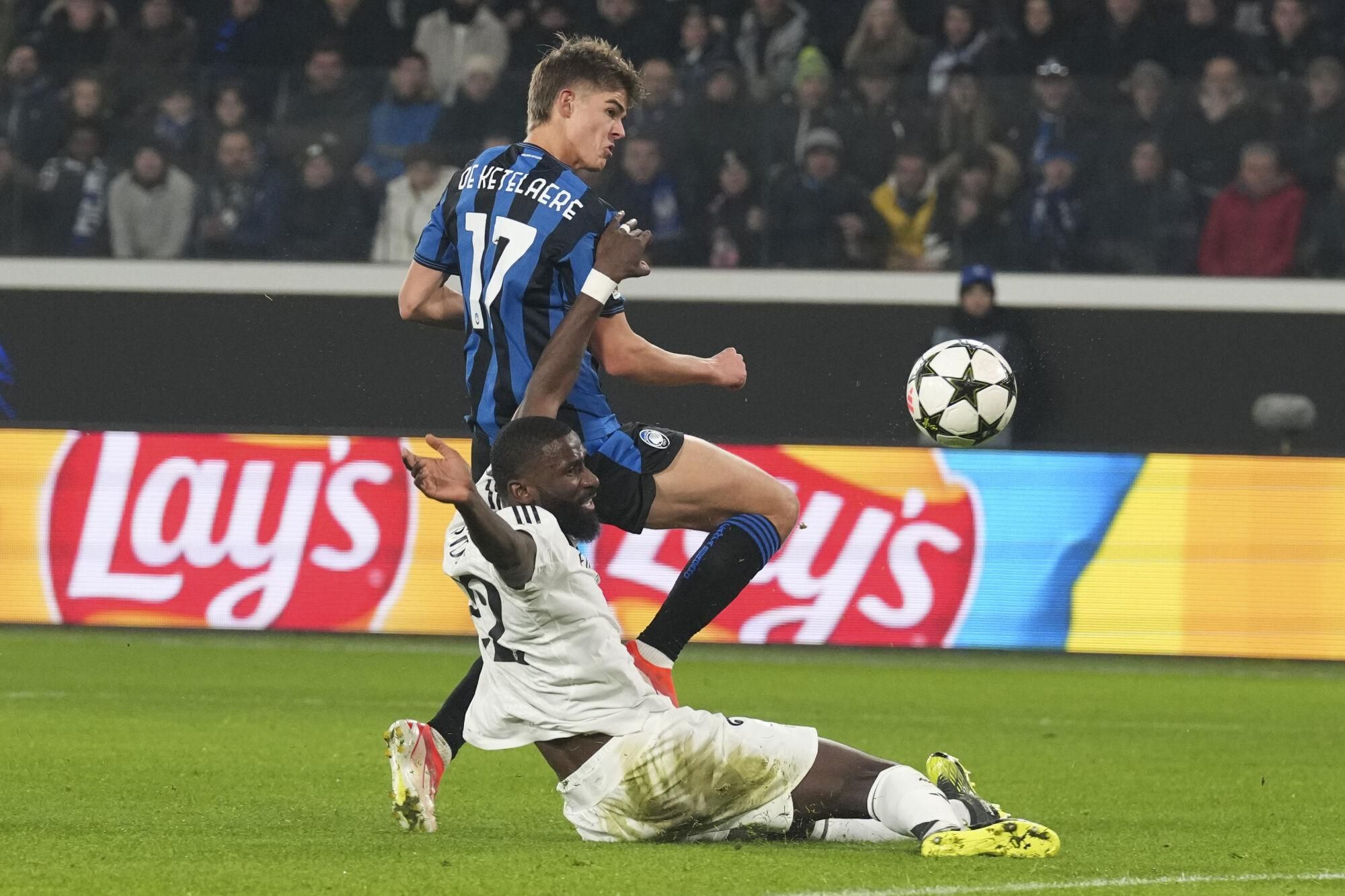 Atalanta's Charles De Ketelaere, top, and Real Madrid's Antonio Rudiger fight for the ball during the Champions League opening phase soccer match between Atalanta and Real Madrid at the Bergamo's stadium, in Bergamo, Italy, Tuesday, Dec. 10, 2024. (AP Photo/Antonio Calanni). EDITORIAL USE ONLY/ONLY ITALY AND SPAIN