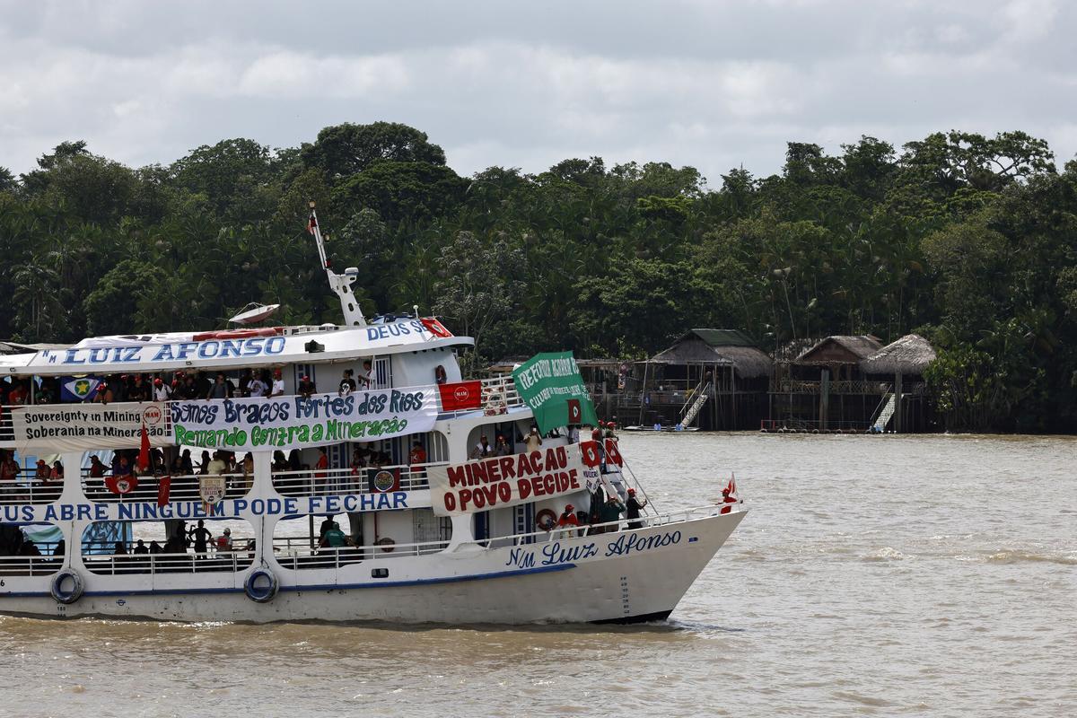 Una embarcación con integrantes de diversos movimientos sociales e indígenas navega por la bahía de Guajará con mensajes de protesta para la cumbre del clima de Belém (COP30).