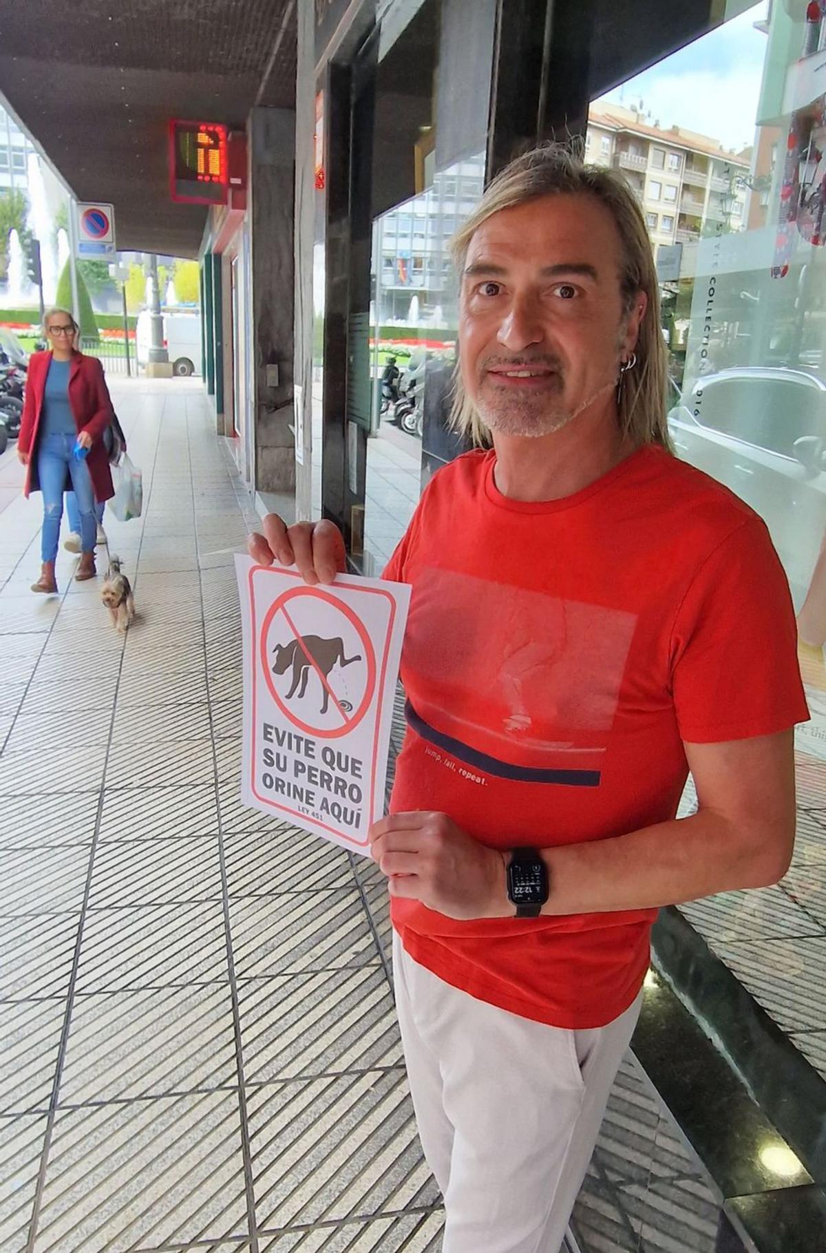 Dominique Ronard, ayer, con uno de los carteles colocados en la calle Marqués de Teverga para pedir civismo a los dueños de los perros. | L. B.