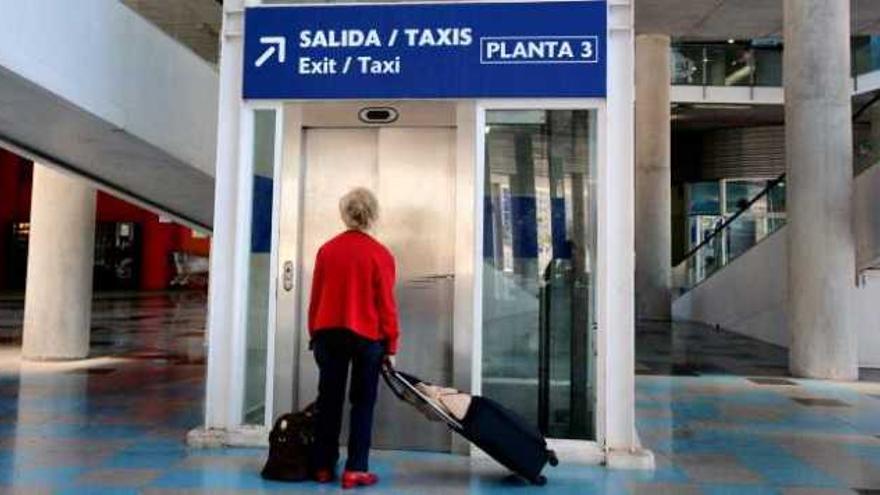 Una turista con maletas frente a un cartel que indica que la parada está en la tercera planta, ayer.