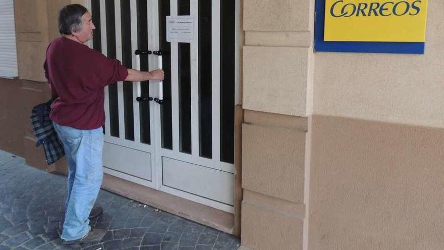 Una mujer se encuentra cerrada la puerta de la oficina de Correos.