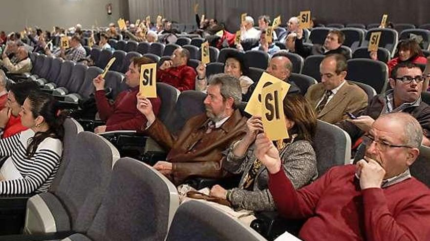 Los asistentes a la asamblea emiten su voto.