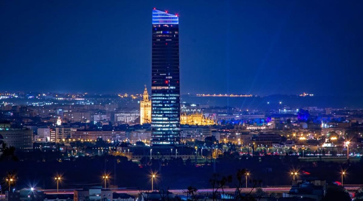 Imagen noctura de Torre Sevilla, con la Giralda al fondo.
