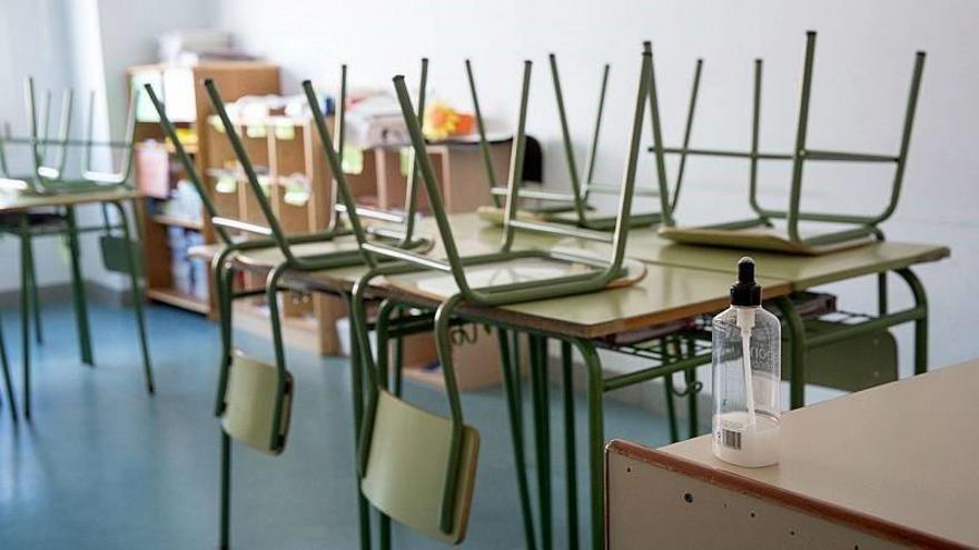 Un aula con sillas recogidas sobre los pupitres.