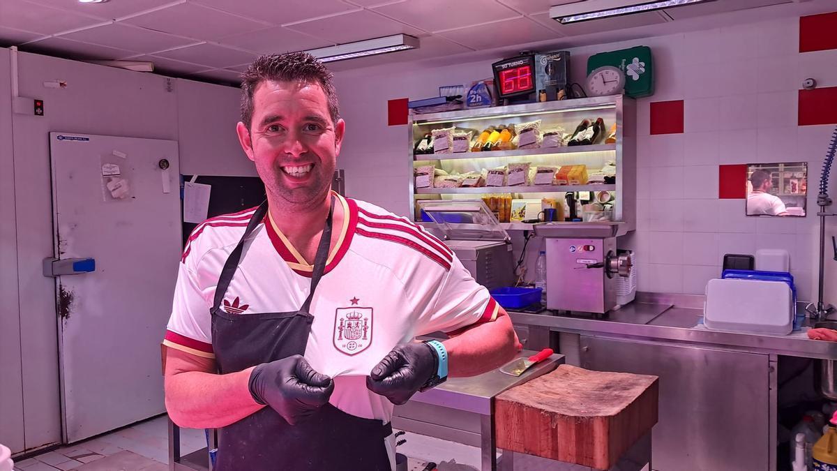 Francisco García luce su camiseta bajo el delantal en la carnicería.