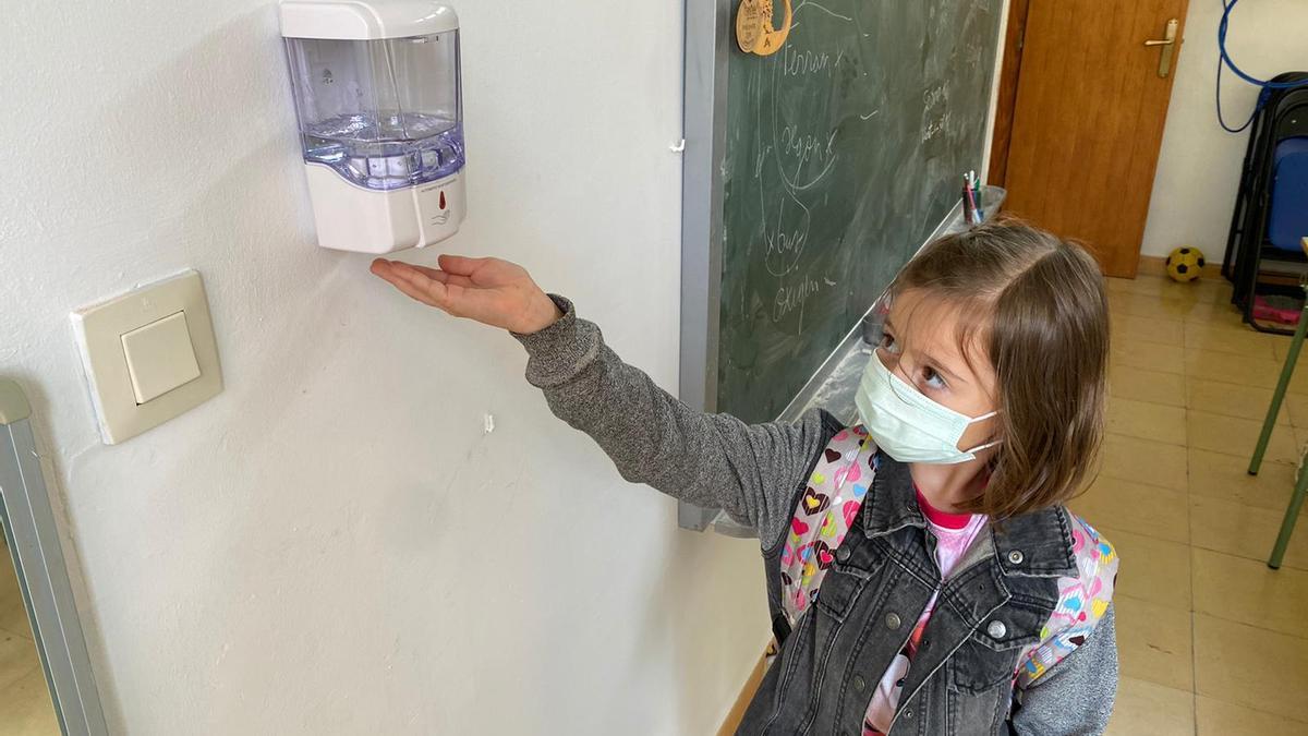 Una escolar de Confrides se pone gel de un dispensador instalado en el colegio. 