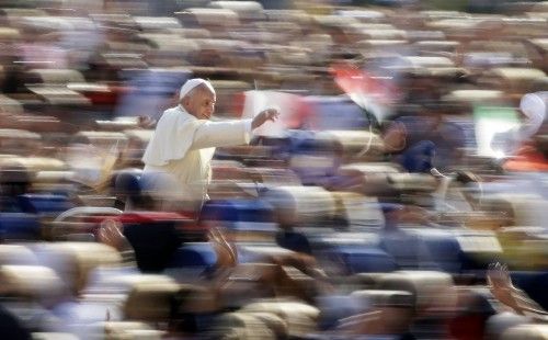 Pope Francis waves as he arrives to lead his weekly audience in Saint Peter's Square at the Vatican