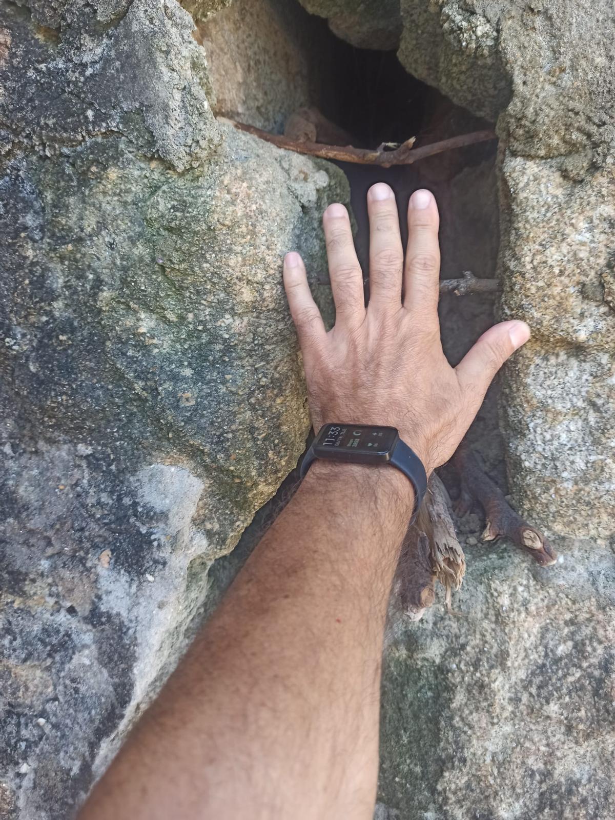 Detalle de una mano, este martes, en la grieta del muro de contención de la playa de Petís (Bueu) para referenciar sus dimensiones.
