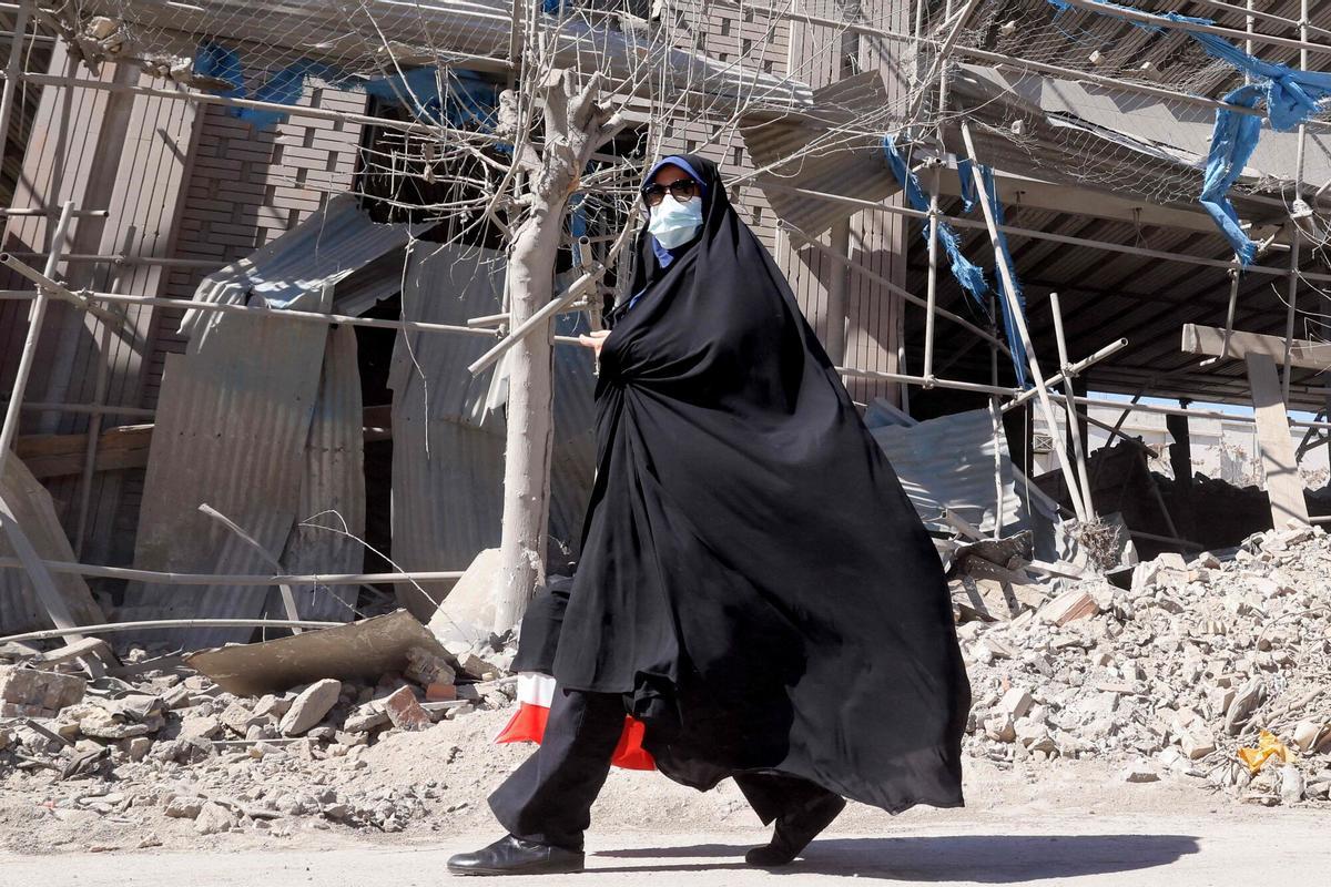 Una mujer pasa delante de un edificio destruido, en Teherán, por los bombardeos de Estados Unidos e Irán.
