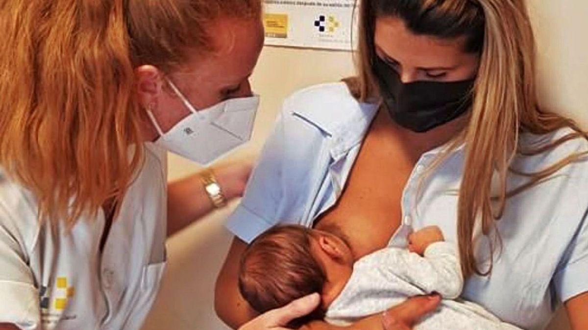 Una mujer da el pecho a su bebé bajo la supervisión de una matrona.