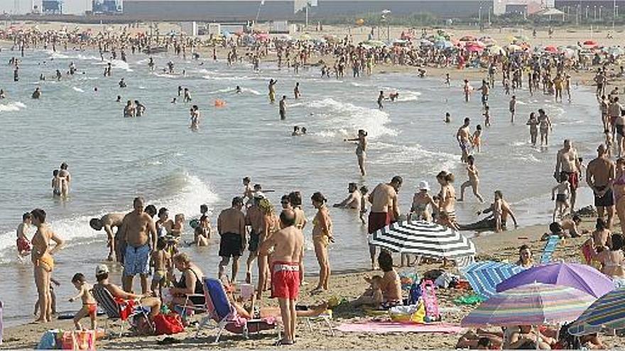 Las grúas del puerto dominan el horizonte de la playa de Sagunt, con bandera azul.  f tortajada