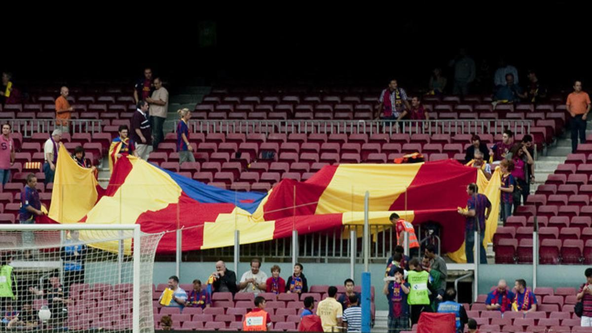 Unos aficionados despliegan una bandera antes del partido.