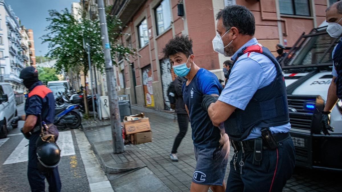 Un agente de los Mossos, con uno de los arrestados en la operación.